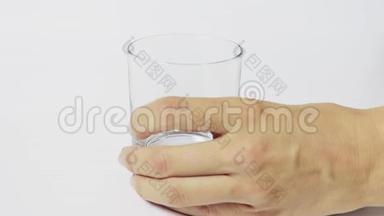 女人`手把一个透明的空玻璃放在白色的桌子上，往里面倒纯净水，然后把<strong>拿下</strong>来